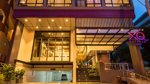 A multi-story hotel with a modern design, featuring large windows, a reception area, and a staircase leading to the entrance. - XQ Pattaya Hotel (Pattaya)