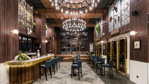 A bar area with a counter, bar stools, and a chandelier. - XQ Pattaya Hotel (Pattaya)