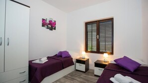 A bedroom with two beds, a wardrobe, and a window with blinds. - Villa Roza- Two-Bedroom Apartment (Mokosica)