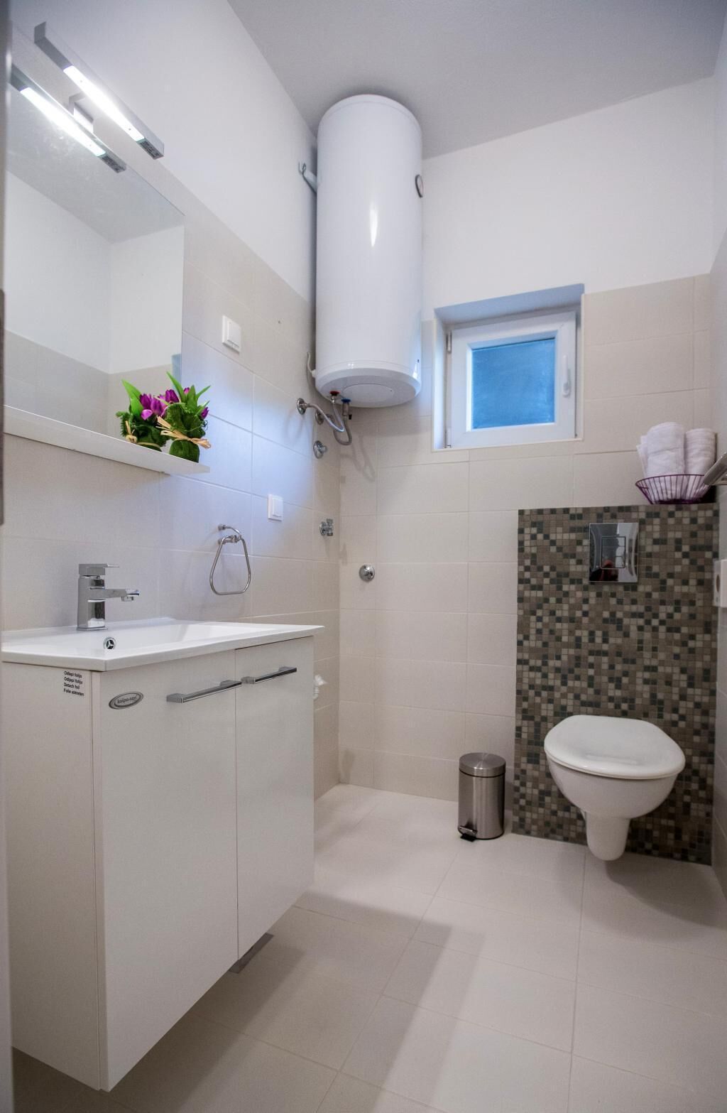 A modern bathroom with a white sink, a toilet, and a shower.