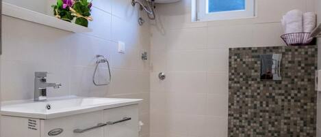 A modern bathroom with a white sink, a toilet, and a shower.
