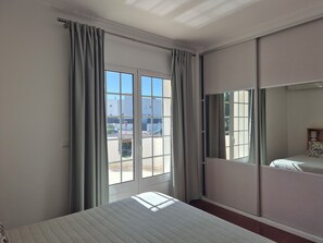 A hotel room with a bed, a sliding door to a balcony, and a view of the outside.