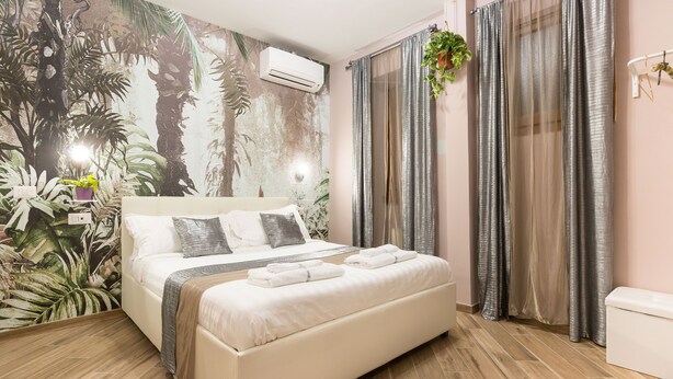 Une chambre à coucher avec un lit, un climatiseur fixé au mur et une fenêtre avec des rideaux.