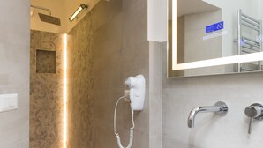 Une salle de bain moderne avec un grand miroir, un lavabo blanc et un espace douche.