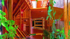 Eine rustikale Holzhütte mit Schlafzimmer im Zwischengeschoss, einem kleinen Fenster und einem Holzbett im oberen Bereich.