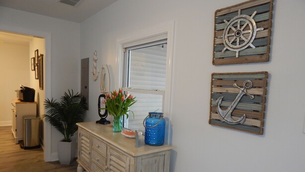 A hallway with a wooden cabinet, a window with blinds, and two wall-mounted nautical-themed decorations. - Newly renovated family home 11/2 blocks from the beach and town center (Sea Isle City)