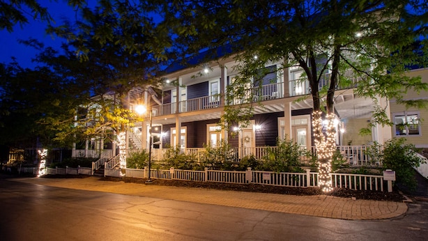 A multi-story building with a balcony on the second floor, a gated entrance, and a well-lit driveway. - Luxury Beachwalk Resort House Closest to Beach includes resort amenities (Michigan City)