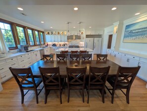 A spacious kitchen with a central island, wooden chairs, and white cabinetry. - Luxurious newly constructed estate nestled in the quiet Talbot Hill neighborhood (Renton)