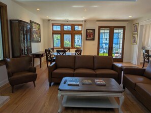 A spacious living room with a brown leather sofa, a coffee table with books, and a dining area with wooden chairs and a table. - Luxurious newly constructed estate nestled in the quiet Talbot Hill neighborhood (Renton)