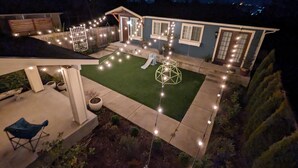 A backyard with a lawn, string lights, a wooden deck, and a small shed. - Luxurious newly constructed estate nestled in the quiet Talbot Hill neighborhood (Renton)
