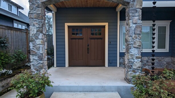 A house with a stone facade, a double door entrance, and a concrete pathway leading to the door. - Luxurious newly constructed estate nestled in the quiet Talbot Hill neighborhood (Renton)