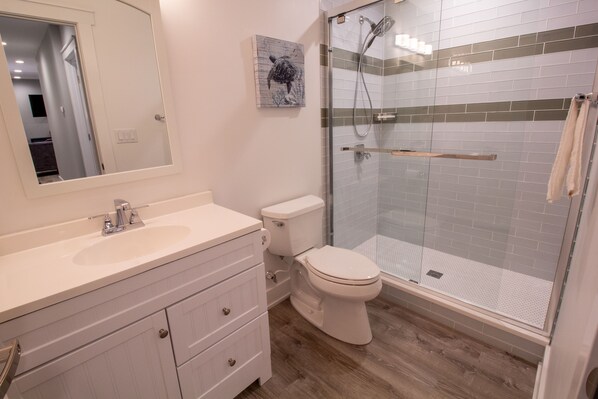 A bathroom with a white sink, toilet, and glass shower enclosure.