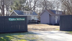 A gated entrance to a campground with two cabins, a gravel driveway, and a sign reading "Camp Willow".