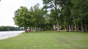 A grassy park area with trees and a lake.