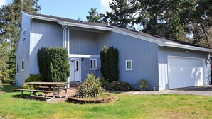 Ein zweistöckiges Haus mit Garage, Veranda und Picknicktisch.