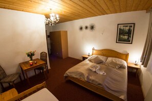Un dormitorio con una cama de madera, una mesita de noche, una mesa con un jarrón de flores y una araña.