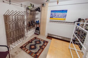 Una habitación con un perchero metálico para zapatos, un póster con motivos de esquí y suelo de madera.