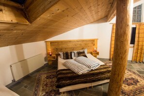 A bedroom with a wooden headboard, a bed with striped bedding, a patterned rug, and a window with curtains.