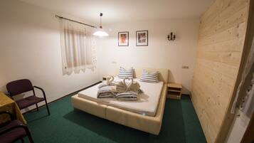 Une petite chambre à coucher, chaleureuse et accueillante, avec un lit, une chaise, une petite table et un mur en bois.