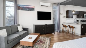 Ein modernes Wohnzimmer mit einem grauen Sofa, einem Couchtisch und einem Fernseher.