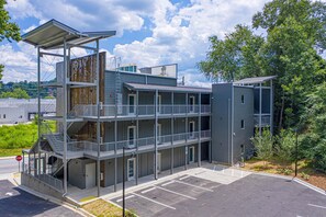 A multi-story building with balconies, a parking lot, and a stop sign.