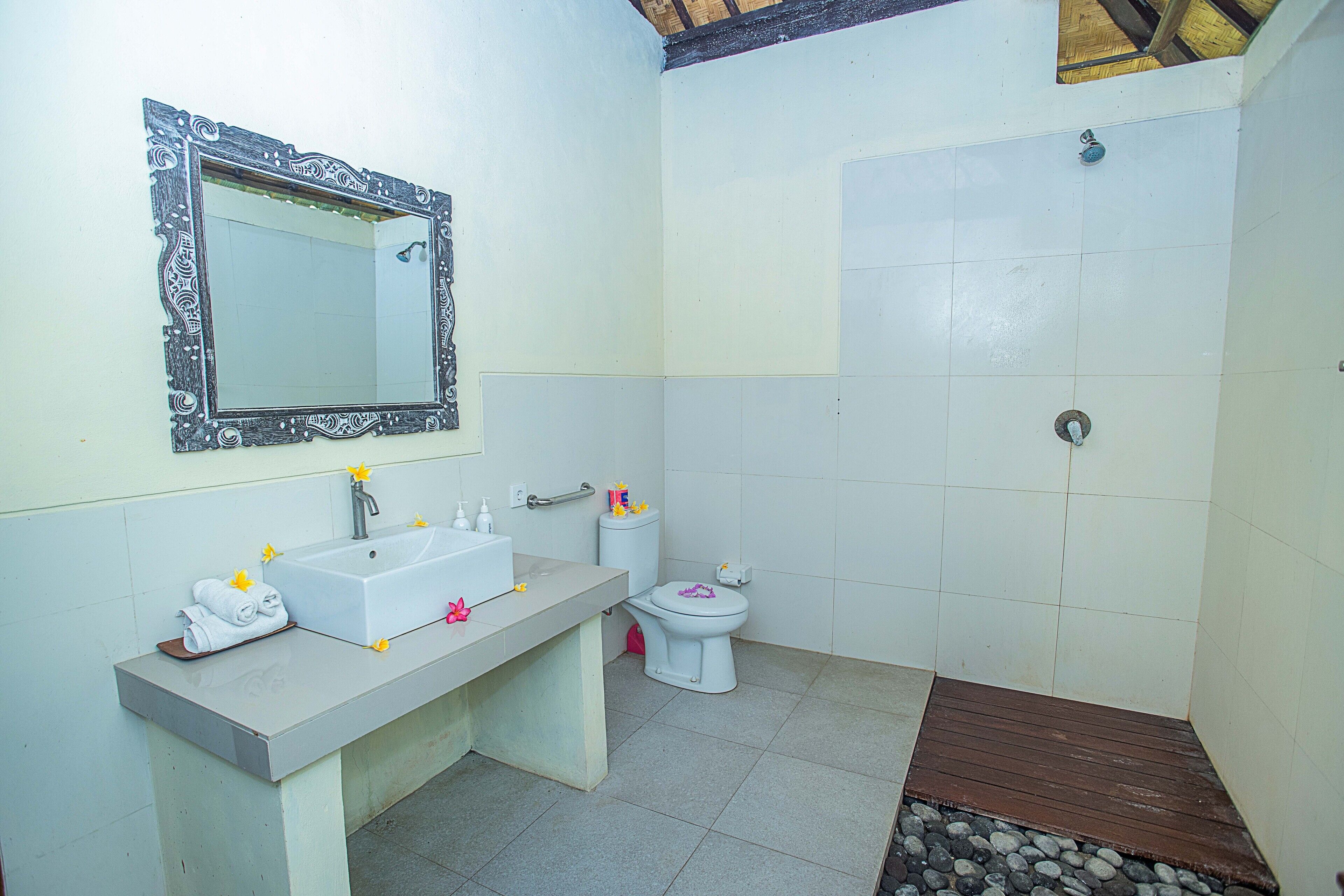 A bathroom with a sink, mirror, toilet, and shower.