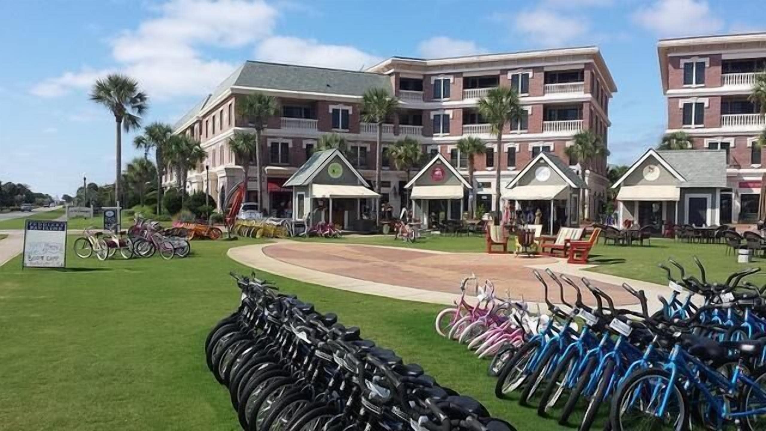 A hotel with multiple floors, outdoor seating areas, and a bike rental service.