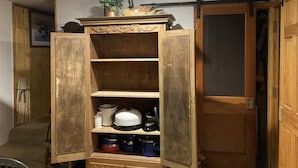Un mueble de madera con puertas abiertas, mostrando utensilios de cocina y utensilios de cocina.