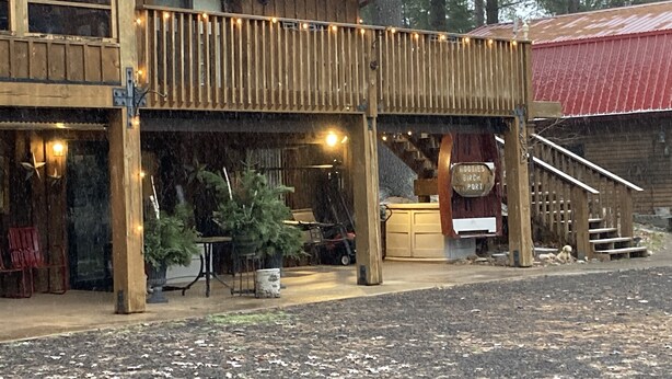 Un edificio de madera con techo rojo, un balcón con luces colgantes y un letrero que dice "Roots Birch Port".