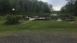 Un parque tranquilo junto al lago con un muelle de madera, un banco y un pequeño bote.