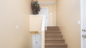 A carpeted staircase leading to a white door, beige walls, and a small plant on the landing. - Paradise Canyon Golf Resort - Luxury Condo M409 (Lethbridge)
