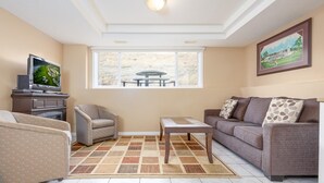 A living room with a sofa, armchair, coffee table, and a TV on a stand. - Paradise Canyon Golf Resort - Luxury Condo M409 (Lethbridge)