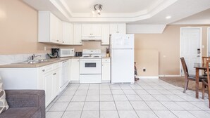 A compact kitchen with white cabinets, a microwave, a stove, and a refrigerator. - Paradise Canyon Golf Resort - Luxury Condo M409 (Lethbridge)