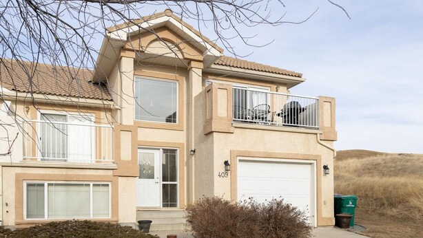 A two-story house with a garage, a balcony, and a small front yard with a fire pit. - Paradise Canyon Golf Resort - Luxury Condo M409 (Lethbridge)