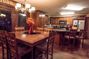 A wooden dining table with chairs, a chandelier, and a vase of flowers. - BEAR CREEK LODGE - Make Bear Creek Lodge Your first choice (Broken Bow)