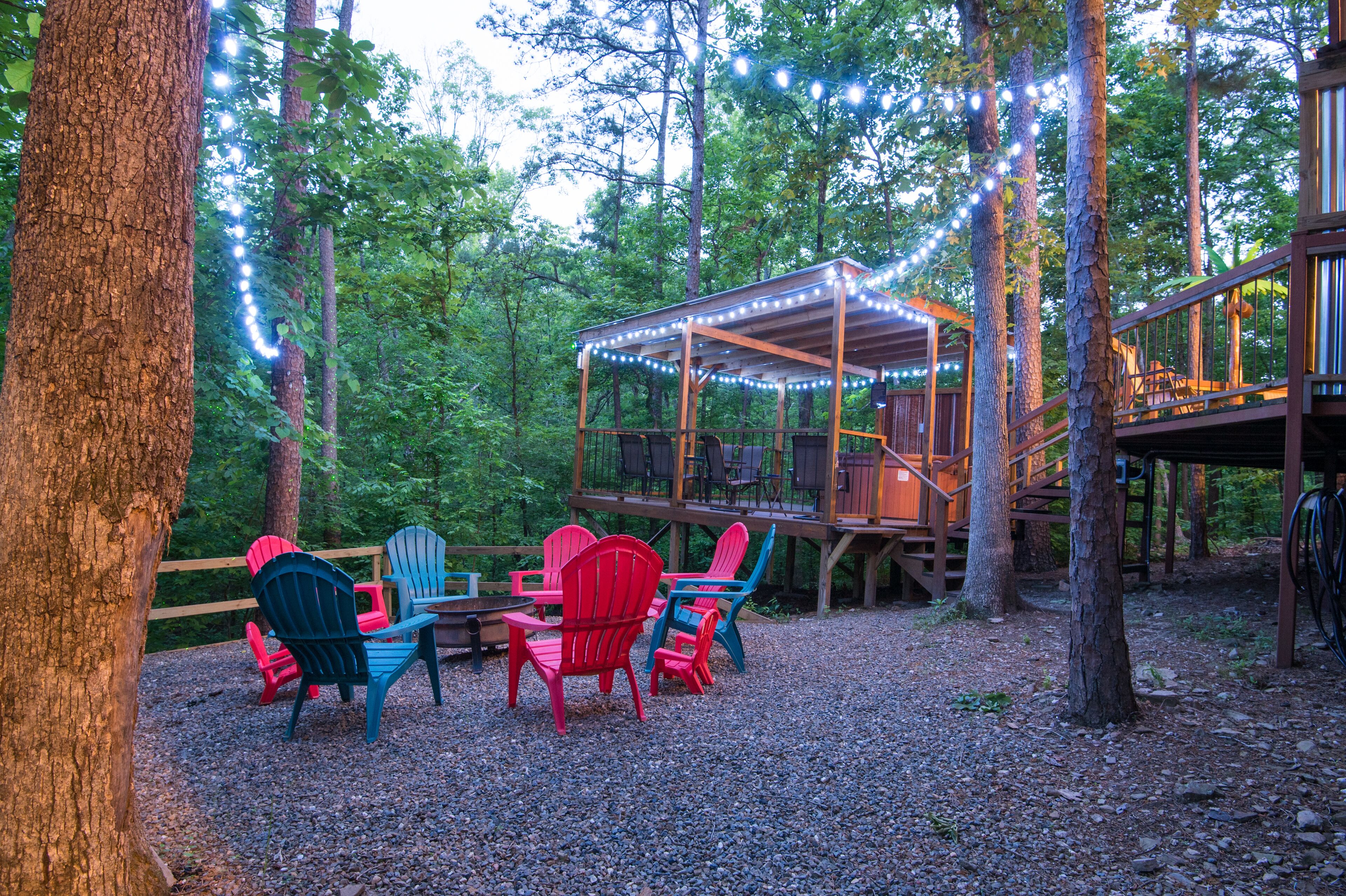 Une terrasse en bois avec des fauteuils Adirondack et des guirlandes lumineuses.