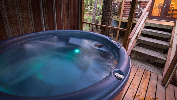Un jacuzzi en una terraza de madera con vistas a un bosque.
