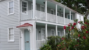 A two-story white house with a porch, a red roof, and a mailbox. - Palm House- Prime Setting and 5 Stars (Charleston)