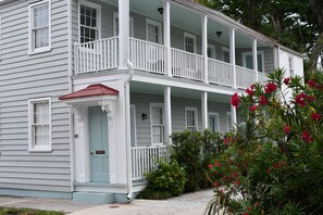 A two-story white house with a porch, a red roof, and a mailbox.