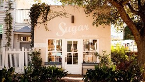 A storefront named 'Sugar Bakeshop' with a white picket fence and plants in front. - Palm House- Prime Setting and 5 Stars (Charleston)