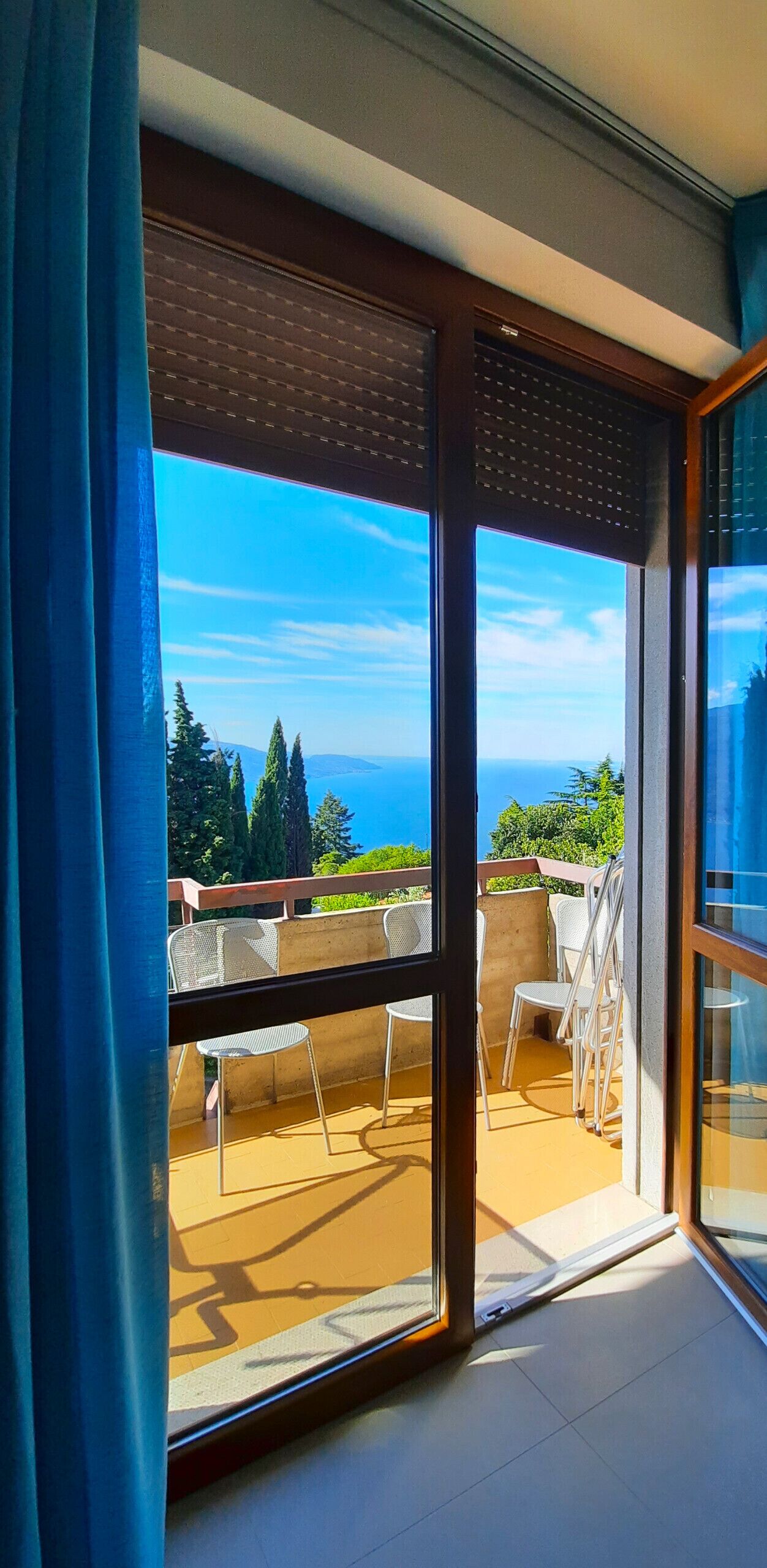 A balcony with a view of the ocean and trees.