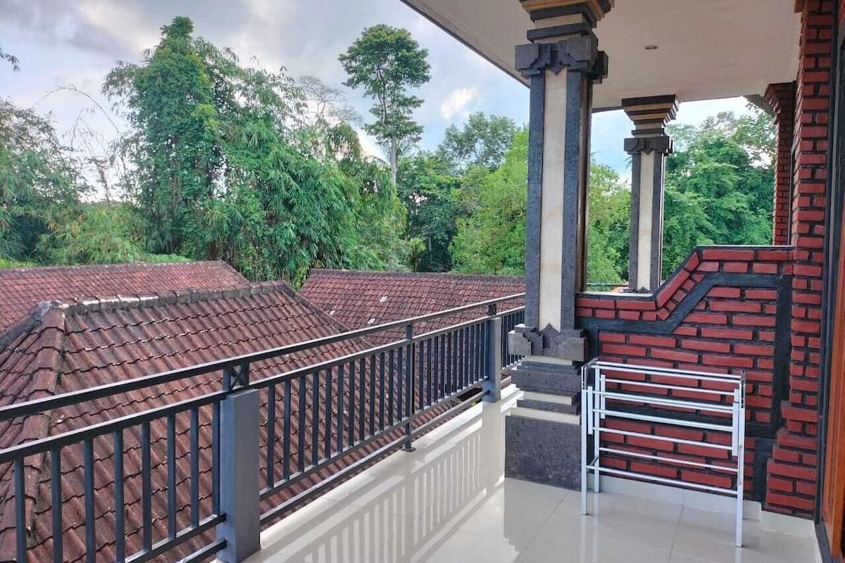 A covered balcony with a tiled roof, a metal railing, and a brick wall.
