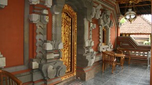 A temple interior with a golden door, stone carvings, and wooden furniture. - Ojeks Homestay (Ubud)