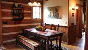 A wooden dining room with a table set for four, a bench, and a fruit bowl. - Blue Ridge Mountain 'Solitude' on The Little River (Sparta)