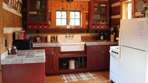 A rustic kitchen with wooden cabinets, a white sink, and a stove. - Blue Ridge Mountain 'Solitude' on The Little River (Sparta)