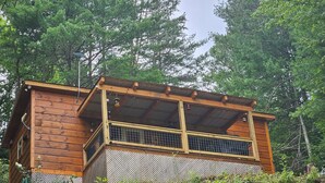 A wooden cabin with a balcony, surrounded by dense forest. - Cedar Bear Cabin - Cozy Mountain View Couples Retreat (Franklin)
