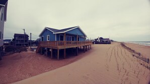 Une maison située en bord de mer, dotée d’une terrasse en bois et de plusieurs étages.