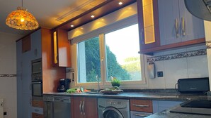 A modern kitchen with built-in appliances, a large window, and a decorative pendant light.
