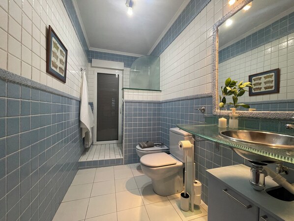 A bathroom with a toilet, sink, and shower area.