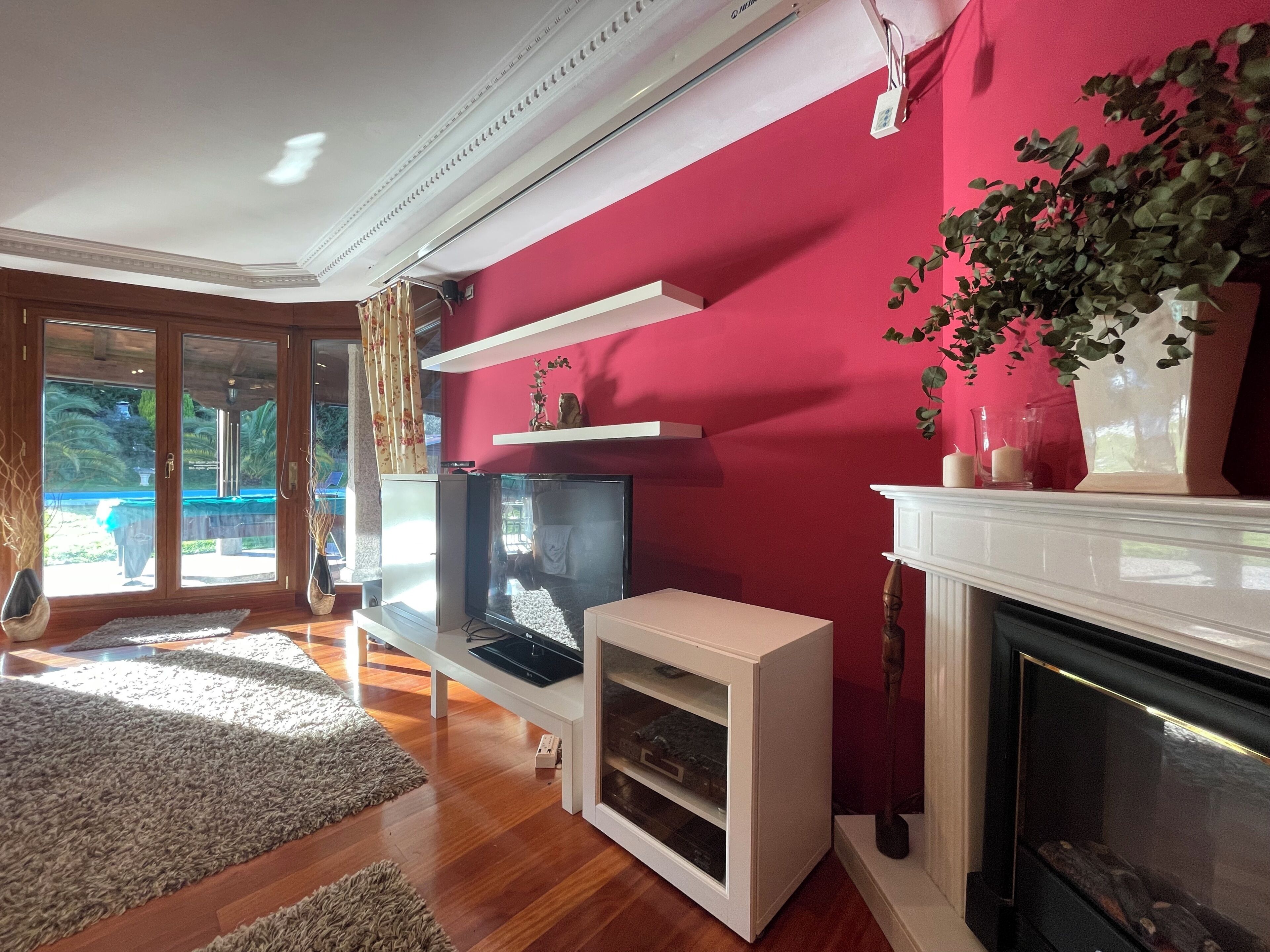 Un salon avec une télévision, une cheminée et un mur rouge.